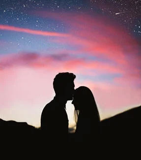A couple kissing under a night sky